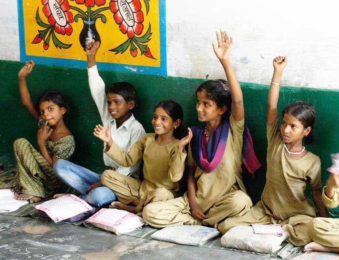 Southeast Asian students sitting on a floor with raised hands