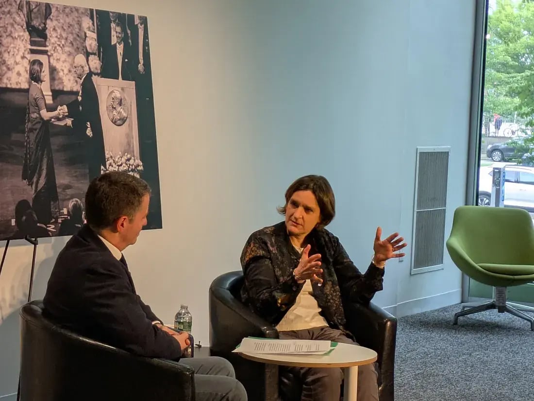 Candid photo of a woman in business casual attire speaking animatedly to a man during a panel.