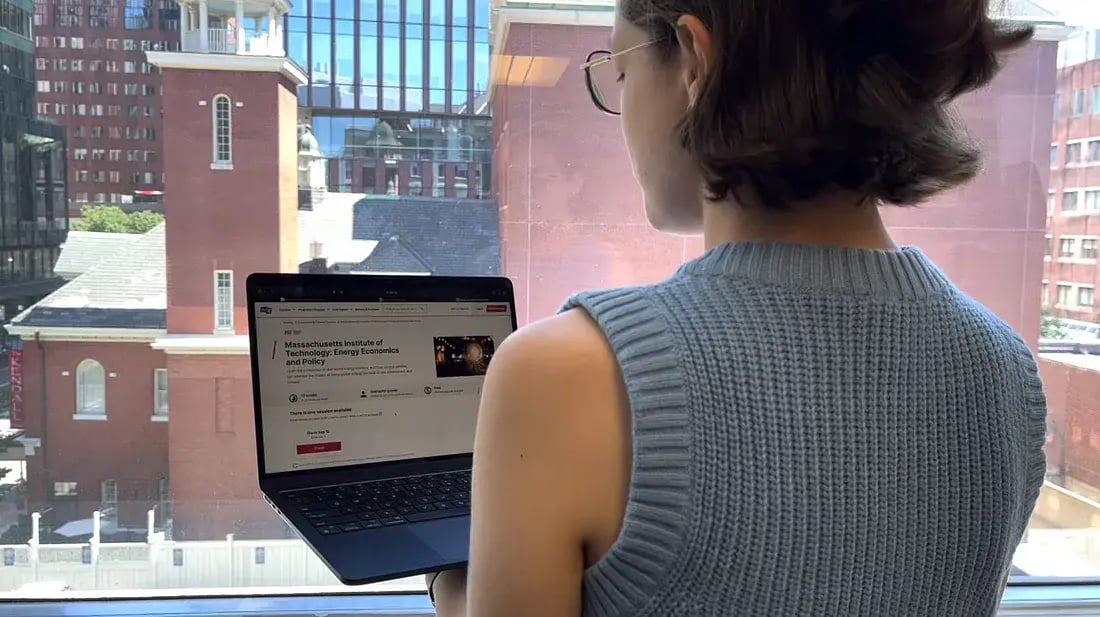 Photo of a learner with glasses looking at an MITx course on an open laptop.