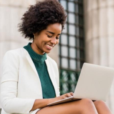 Young African American woman on a laptop is seated and smiling