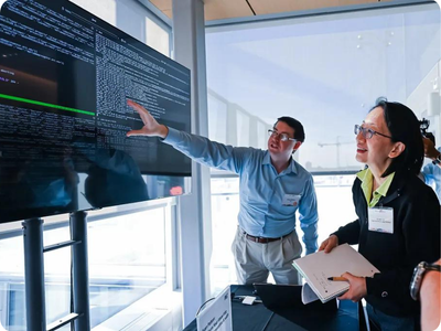 A researcher points at a screen while other people look at the screen.