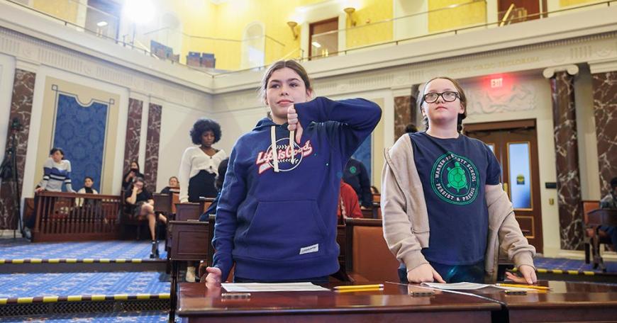 Two female middle school students standing in the chambers of the Edward M. Kennedy Institute for the U.S. Senate